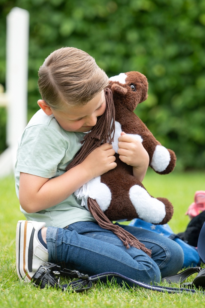 Pinto HKM Kids Cuddle Pony, tenu dans les bras d'un enfant
